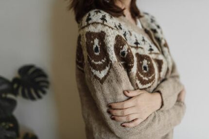 Close-up of a person wearing a cozy bear-design knitted sweater indoors.